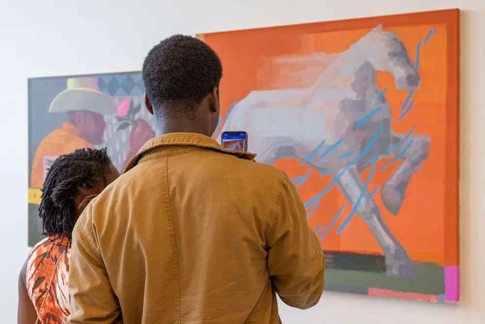 Visitors looking at a large orange painting of a horse