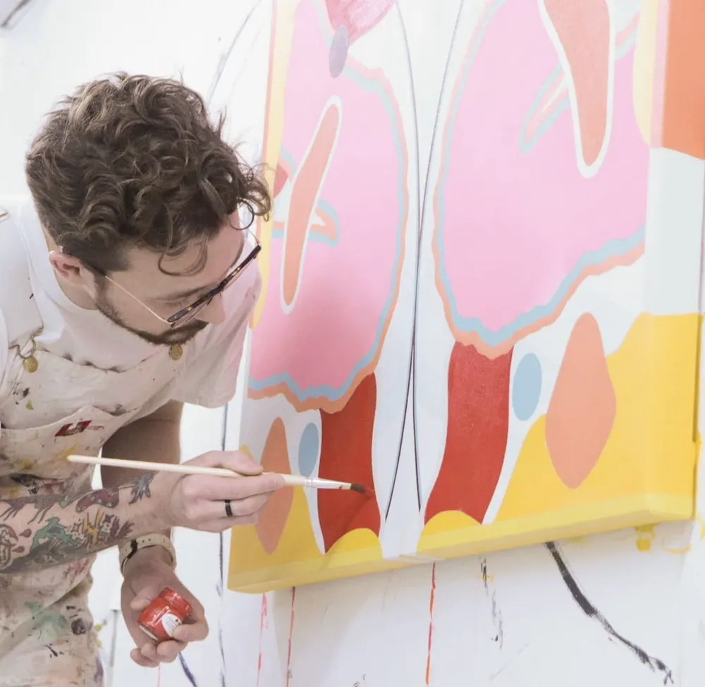 An artist painting a large pink and yellow canvas
