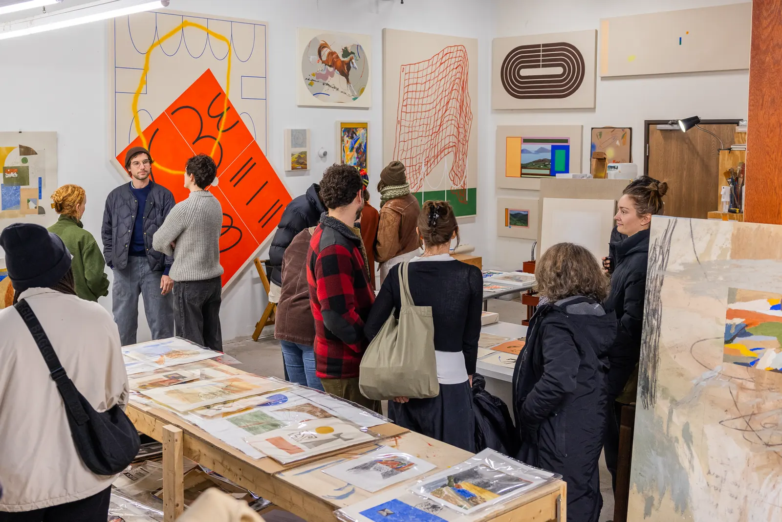 Visitors looking through artwork on tables in an artist's studio