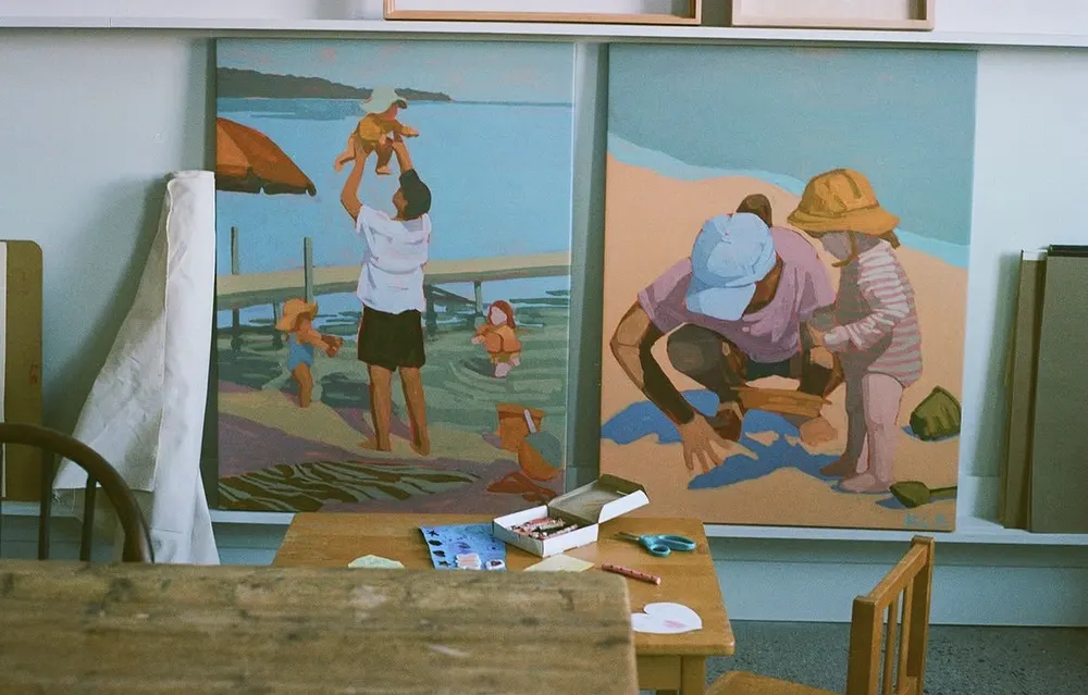Large beach-scene paintings in progress in a studio