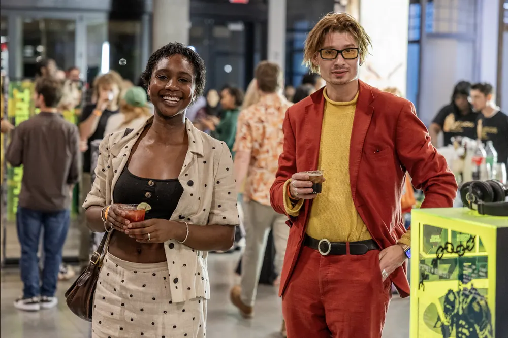 Two guests smiling at a crowded art event
