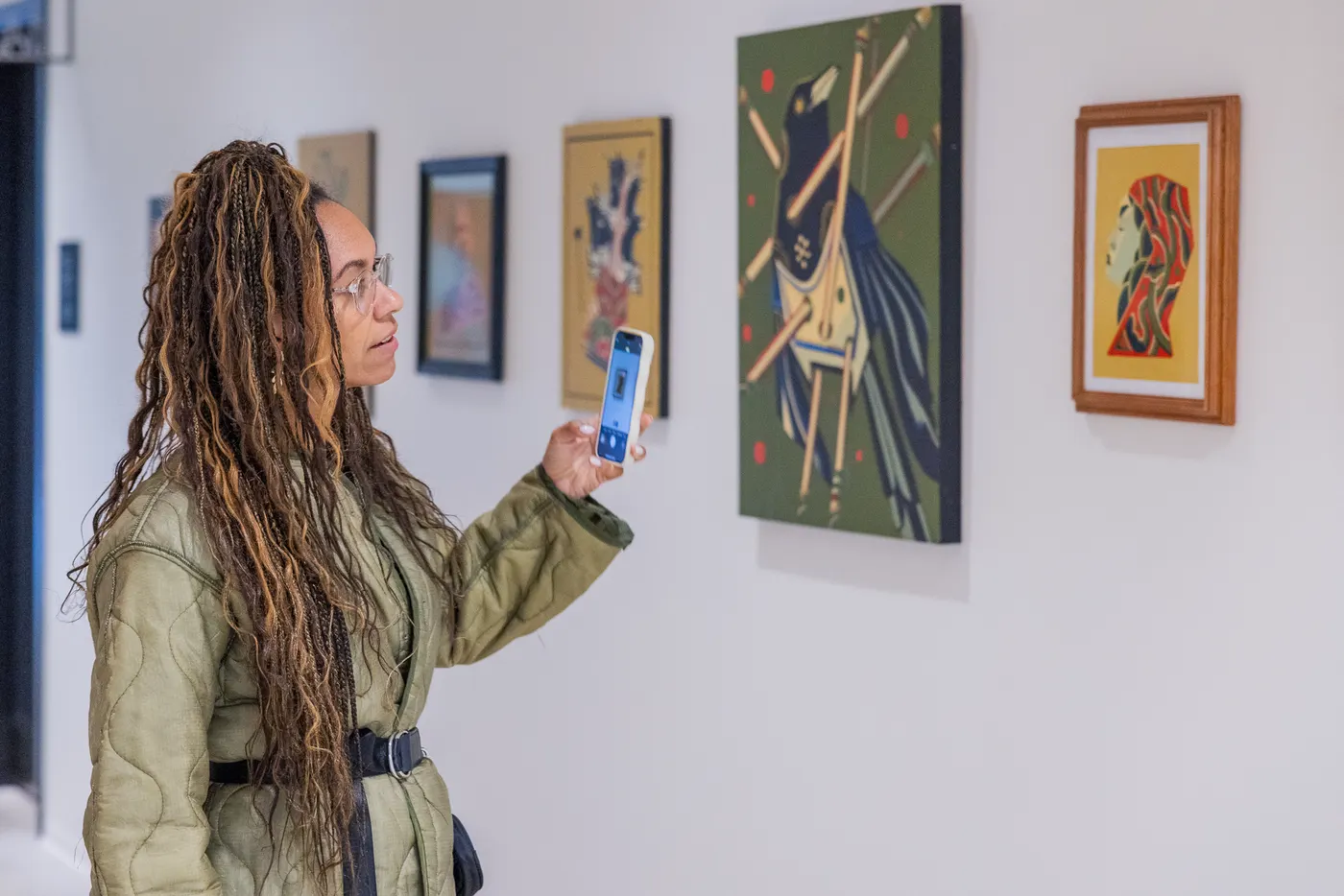 A visitor photographing paintings in a gallery with her phone