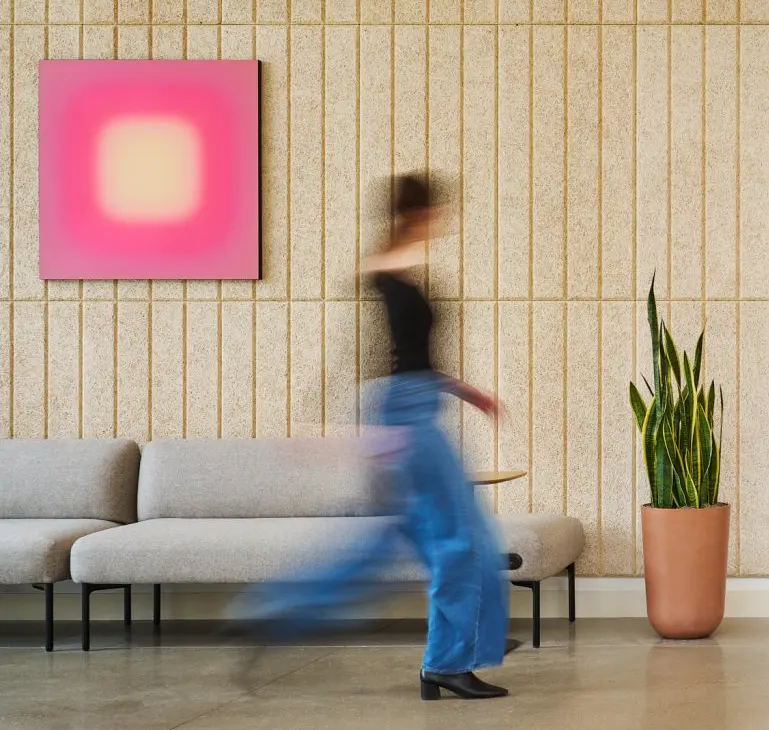 A person walking past a pink abstract painting in a lounge