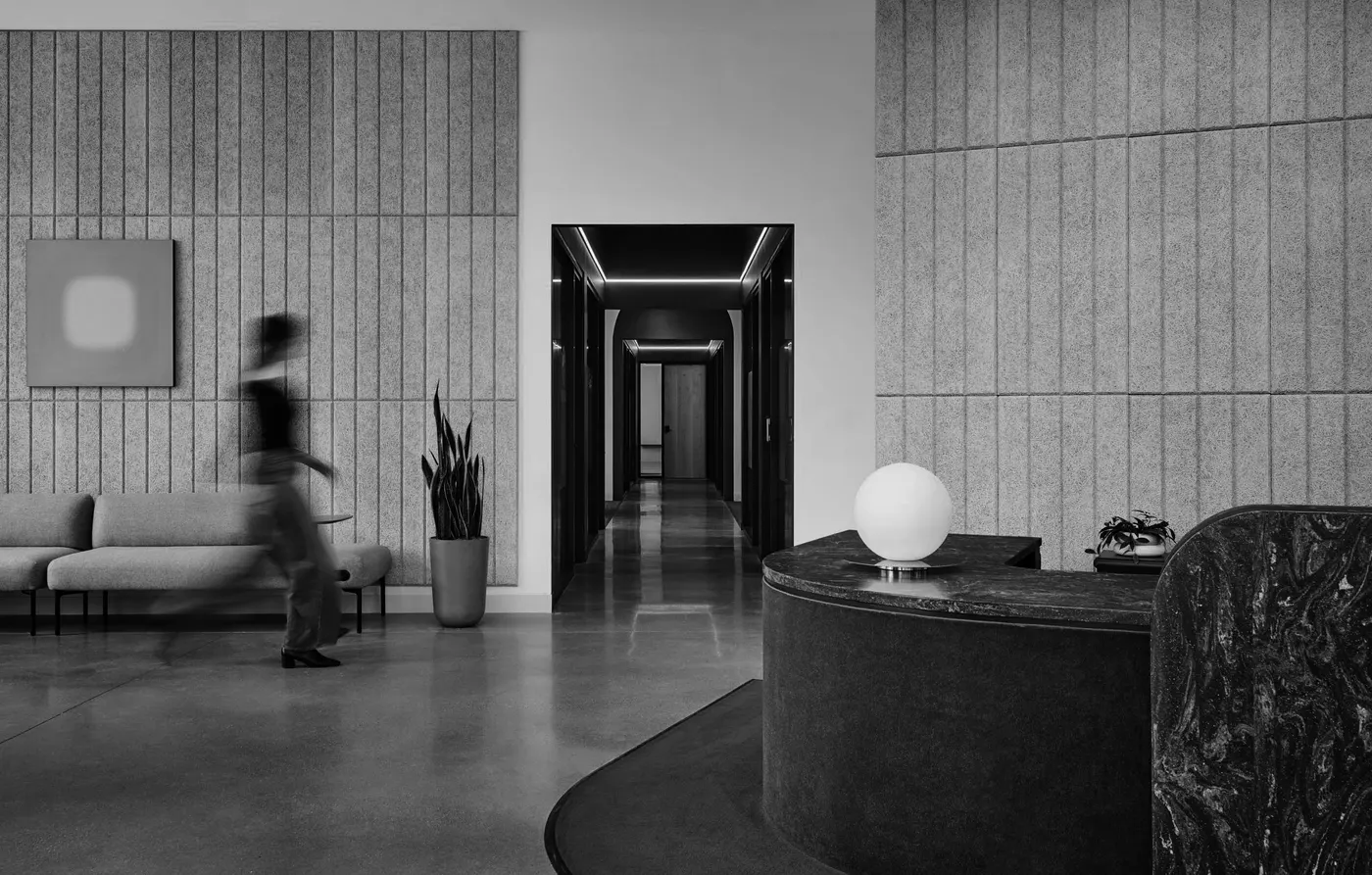 A black-and-white office lobby with a person walking past original work