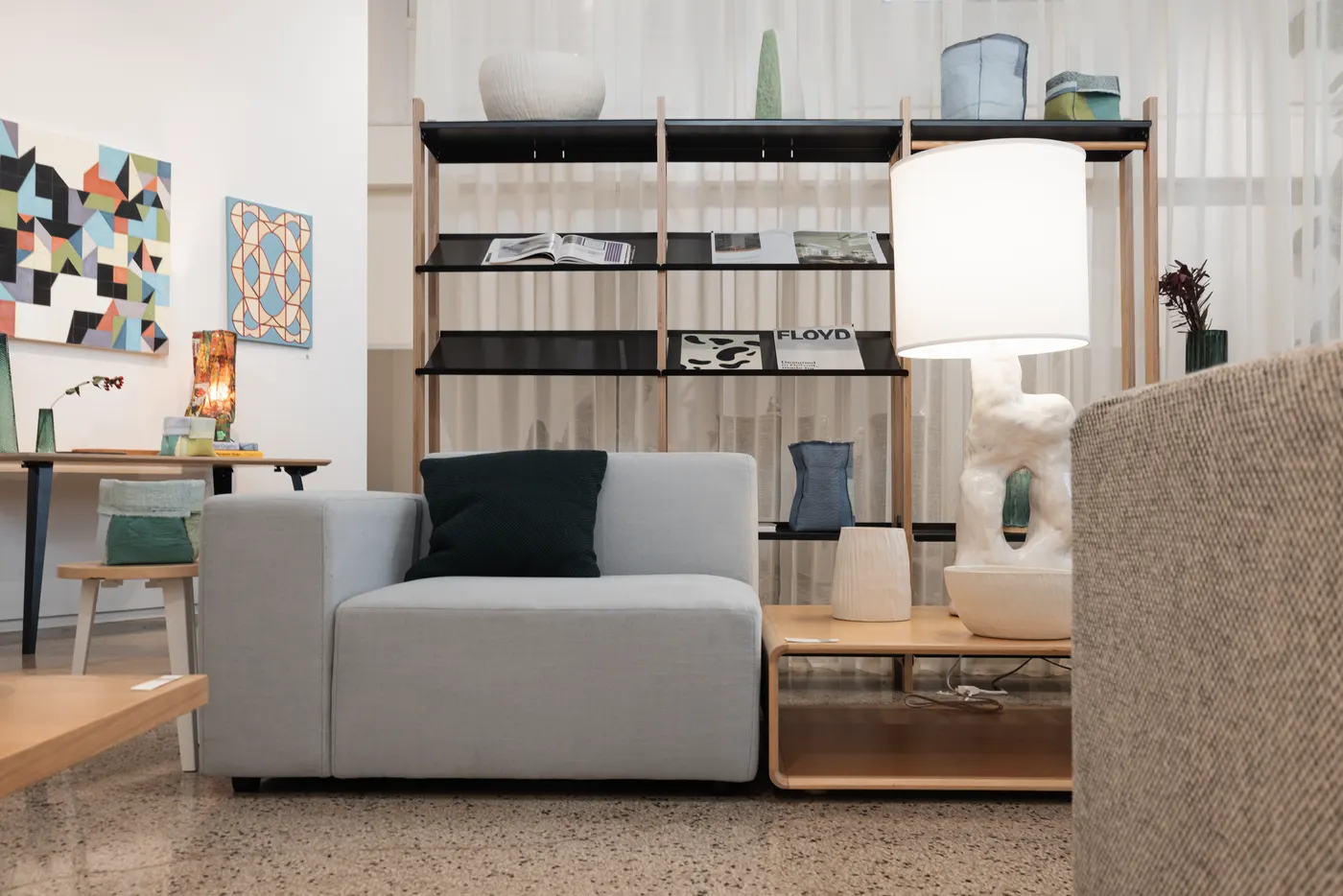 A retail showroom with a sofa, shelving and original art on the walls